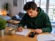 Jeune actif calculant son budget loyer dans un studio moderne et lumineux